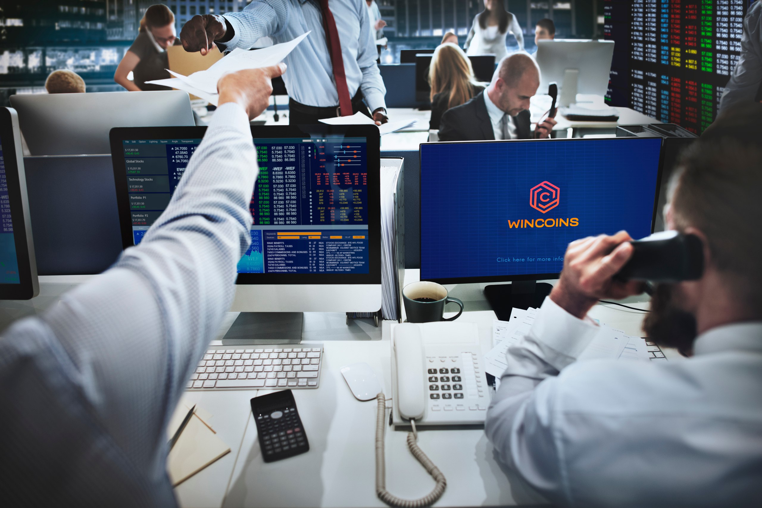 Wincoins logo present on computer monitor People in office with phone